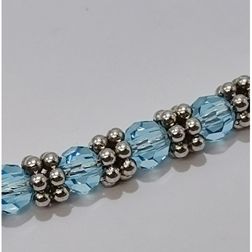 672 - An 18 carat white gold aquamarine necklace, faceted round blue stones spaced by pairs of six white-g... 