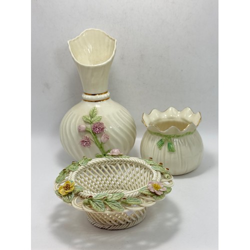 119 - Three pieces of Belleek pottery including String Bag Pot, Scroll Flower ink Irish Vase with gold rim... 