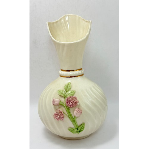 119 - Three pieces of Belleek pottery including String Bag Pot, Scroll Flower ink Irish Vase with gold rim... 