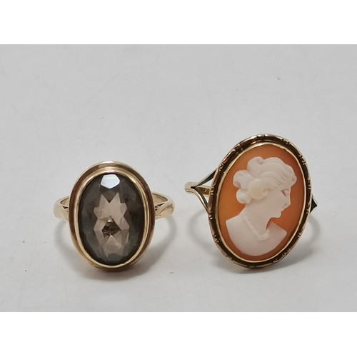  Two 9 carat gold rings, the first collet-set with an oval smoky quartz to pierced scroll shoulders, ... 
