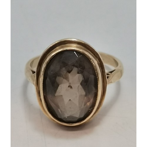  Two 9 carat gold rings, the first collet-set with an oval smoky quartz to pierced scroll shoulders, ... 