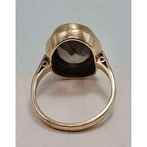  Two 9 carat gold rings, the first collet-set with an oval smoky quartz to pierced scroll shoulders, ... 