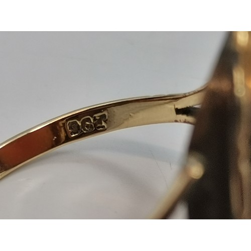  Two 9 carat gold rings, the first collet-set with an oval smoky quartz to pierced scroll shoulders, ... 