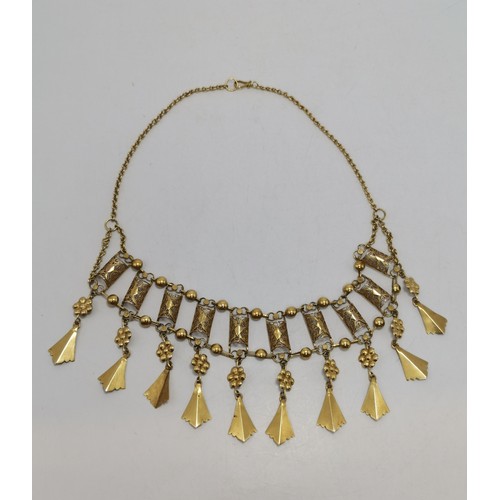 539 - A fancy yellow metal fringe necklace, with ten filigree half-barrel links each hung below with a flo... 
