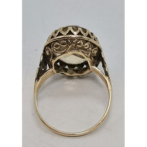 541 - Two 9 carat gold gemstone rings, the first a large oval citrine to a fancy carved c-scroll openwork ... 