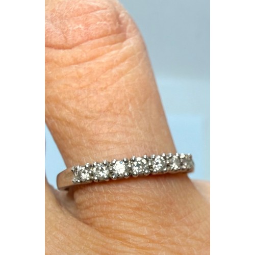  A platinum half-hoop ring, claw-set with seven round white stones, stamped 950 and hallmarked London... 