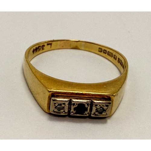574 - An 18 carat gold three-stone ring, the flat top set with a central round blue stone flanked by an il... 