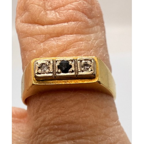 574 - An 18 carat gold three-stone ring, the flat top set with a central round blue stone flanked by an il... 