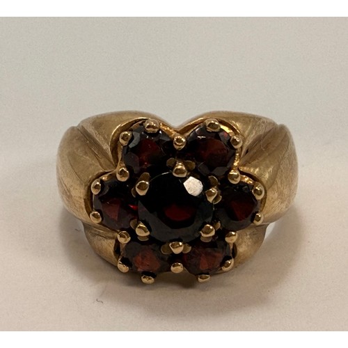  A large 9 carat gold garnet cluster ring, the seven claw-set graduated round stones as a flowerhead ... 