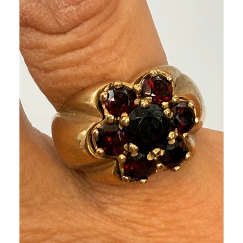  A large 9 carat gold garnet cluster ring, the seven claw-set graduated round stones as a flowerhead ... 