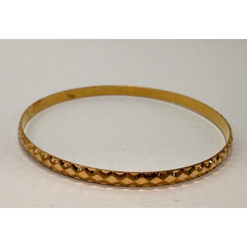 590 - A 9 carat gold hinge-opening bangle with carved leaf-style decoration to a banded ground, hallmarked... 