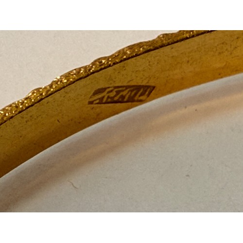 590 - A 9 carat gold hinge-opening bangle with carved leaf-style decoration to a banded ground, hallmarked... 