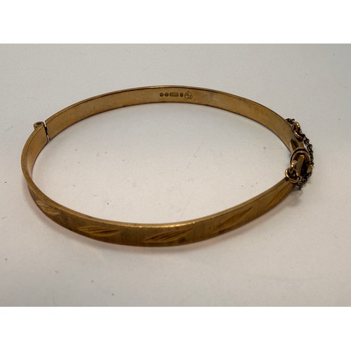 590 - A 9 carat gold hinge-opening bangle with carved leaf-style decoration to a banded ground, hallmarked... 