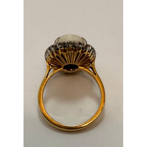 599 - A large opal and diamond cluster ring, the claw-set oval cabochon enclosed by a band of twenty-two e... 