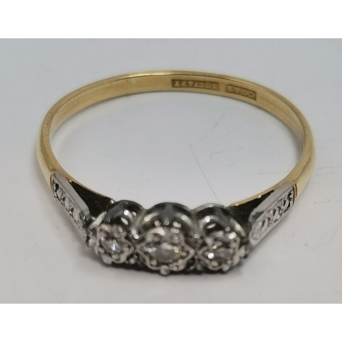  A three-stone ring, illusion-set with graduated round diamonds in a raised openwork mount with carve... 