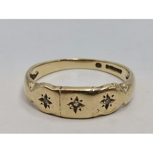  A three-stone ring, illusion-set with graduated round diamonds in a raised openwork mount with carve... 