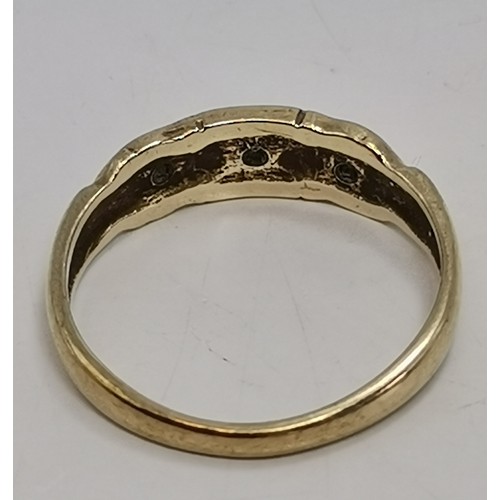  A three-stone ring, illusion-set with graduated round diamonds in a raised openwork mount with carve... 