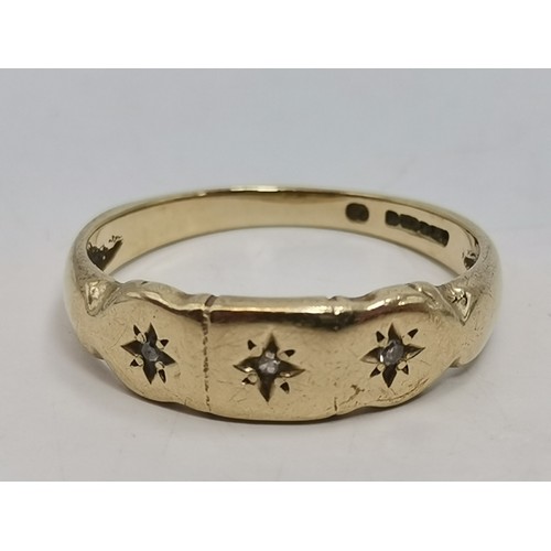  A three-stone ring, illusion-set with graduated round diamonds in a raised openwork mount with carve... 