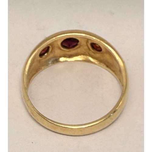  A 9 carat gold three-stone garnet ring, the broad tapering shank with a trio of graduated round ston... 