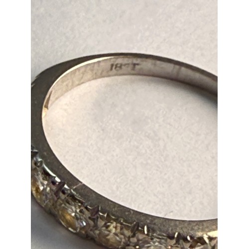  A white gold half hoop ring, set with eight graduated round white stones, stamped '18CT'. Ring size ... 