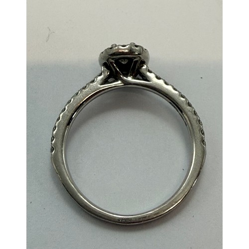  A platinum diamond engagement ring, the central oval brilliant cut stone enclosed by a halo of round... 