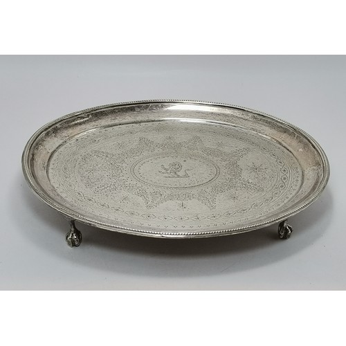 A George III silver teapot stand or salver by Thomas Wallis (II) & Jonathan Hayne, London 1817, oval with bead border, the shallow dished centre flat-chased with a crest enclosed by bands of foliate and star decoration, raised on four ball-and-claw feet. Approx. 20cm by 16.5cm, 7.7 troy ounces
