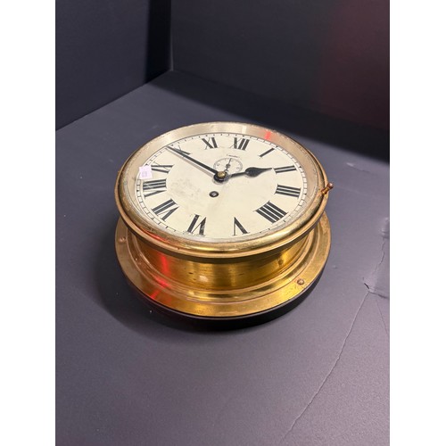 19 - A ships brass wall clock ( made in England ) 25cm diameter with key