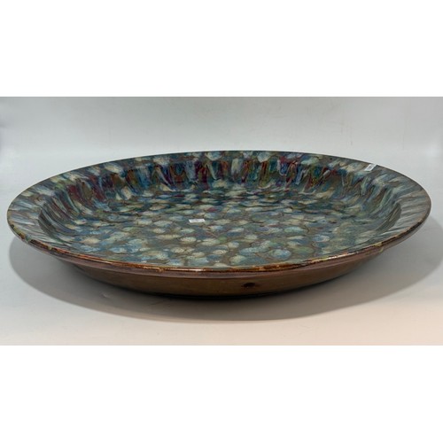 24 - Large contemporary studio pottery charger or shallow bowl.  The surface is glazed with a multi colou... 