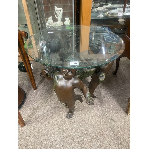 584 - A composite table formed as three putti with circular glass top, 60cm high, 60cm wide