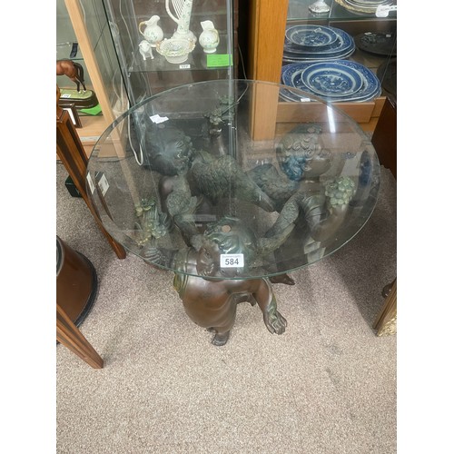 584 - A composite table formed as three putti with circular glass top, 60cm high, 60cm wide