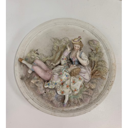 320 - Three bisque porcelain wall plaques featuring high-relief scenes of courting couples.  D 25 cm.