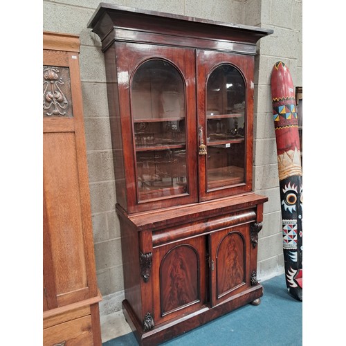 1014 - Victorian Mahogany glazed cupboard bookcase with arched doors and mounted cornice.  Two shelves in b... 