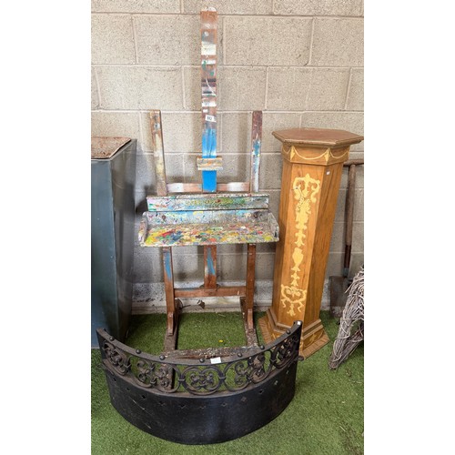 952 - A vintage artist's easel; together with a curved black-painted fire kerb; and a scumbled hexagonal t... 