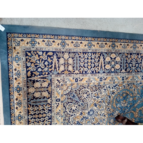 1019 - A large wool rug in blues, cream and gold with floral decorations. 4.2m x 2.8m