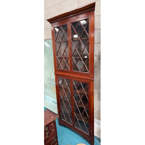 994 - A large repro mahogany double corner cabinet, with dentil cornice over astragal glazed pair of cupbo... 