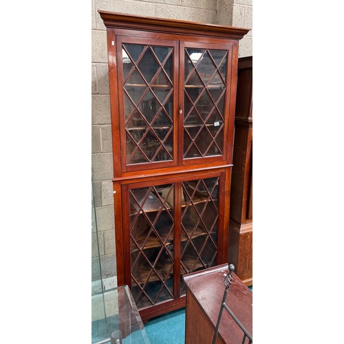 994 - A large repro mahogany double corner cabinet, with dentil cornice over astragal glazed pair of cupbo... 