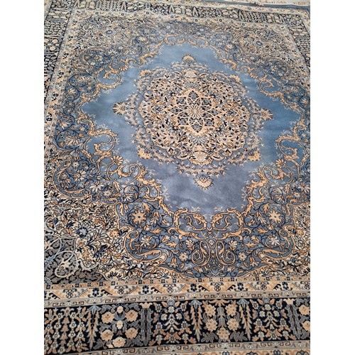 1019 - A large wool rug in blues, cream and gold with floral decorations. 4.2m x 2.8m