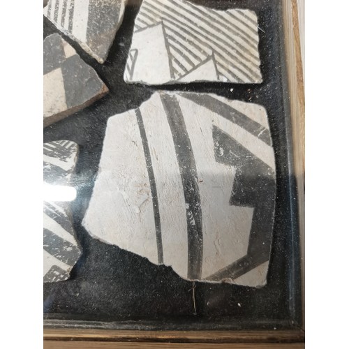12 - A framed display containing Native American Anasazi pottery shards and some stones. H