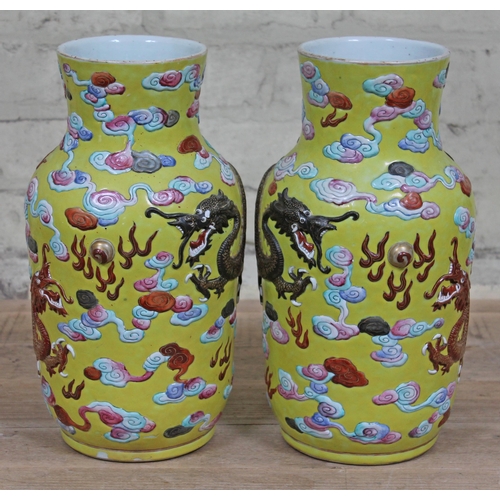 388 - A pair of Chinese yellow ground porcelain vases, 19th Century, decorated in relief with dragons and ... 