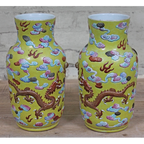 388 - A pair of Chinese yellow ground porcelain vases, 19th Century, decorated in relief with dragons and ... 