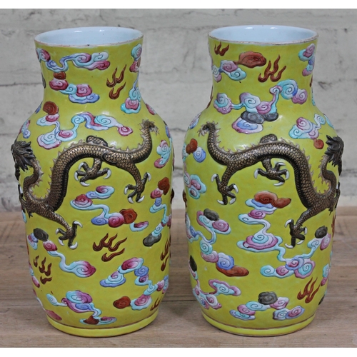 388 - A pair of Chinese yellow ground porcelain vases, 19th Century, decorated in relief with dragons and ... 