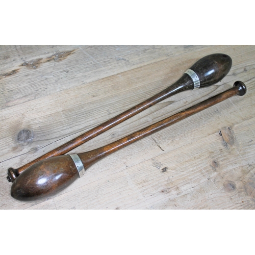 446 - A pair of Edwardian turned wooden clubs with white metal mounts inscribed 'M Woodcock May 1910'.