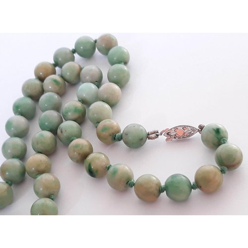 104 - A single strand of 102 jade beads with hallmarked 9 carat white gold clasp, length 112cm, bead diame... 