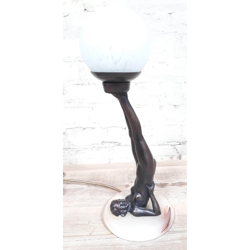 58 - A contemporary Art Deco style lamp formed as a nude lady holding a glass globular shade with her fee... 