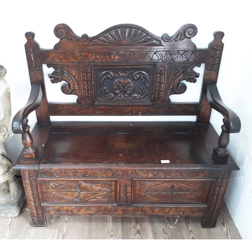 92 - A carved oak bench with lift seat, width 106cm, depth 42cm, height102cm.