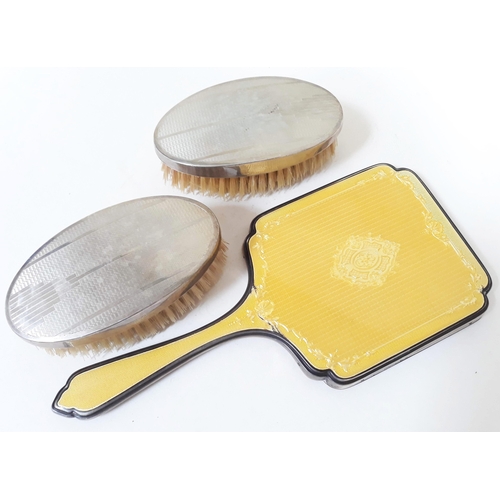 380 - Hallmarked silver comprising a silver and enamel mirror and a pair of silver backed brushes.