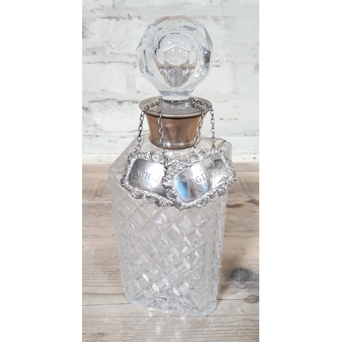 425 - A cut glass decanter with hallmarked silver collar and two hallmarked silver decanter labels.