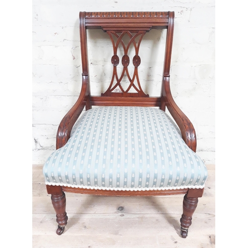 83 - A late Victorian nursing chair with acanthus carved arms and striped blue/cream upholstered seat.