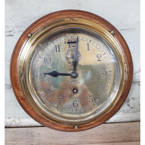 91 - A ship's brass clock mounted on oak, the dial inscribed 'Barkers Kensington', dial diam. 17cm.