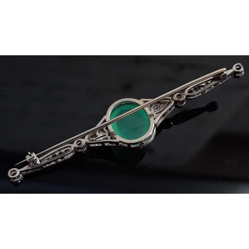 103 - An Art Deco diamond encrusted and jade cabochon brooch, the central stone approx. 19mm x 11mm x 6mm,... 